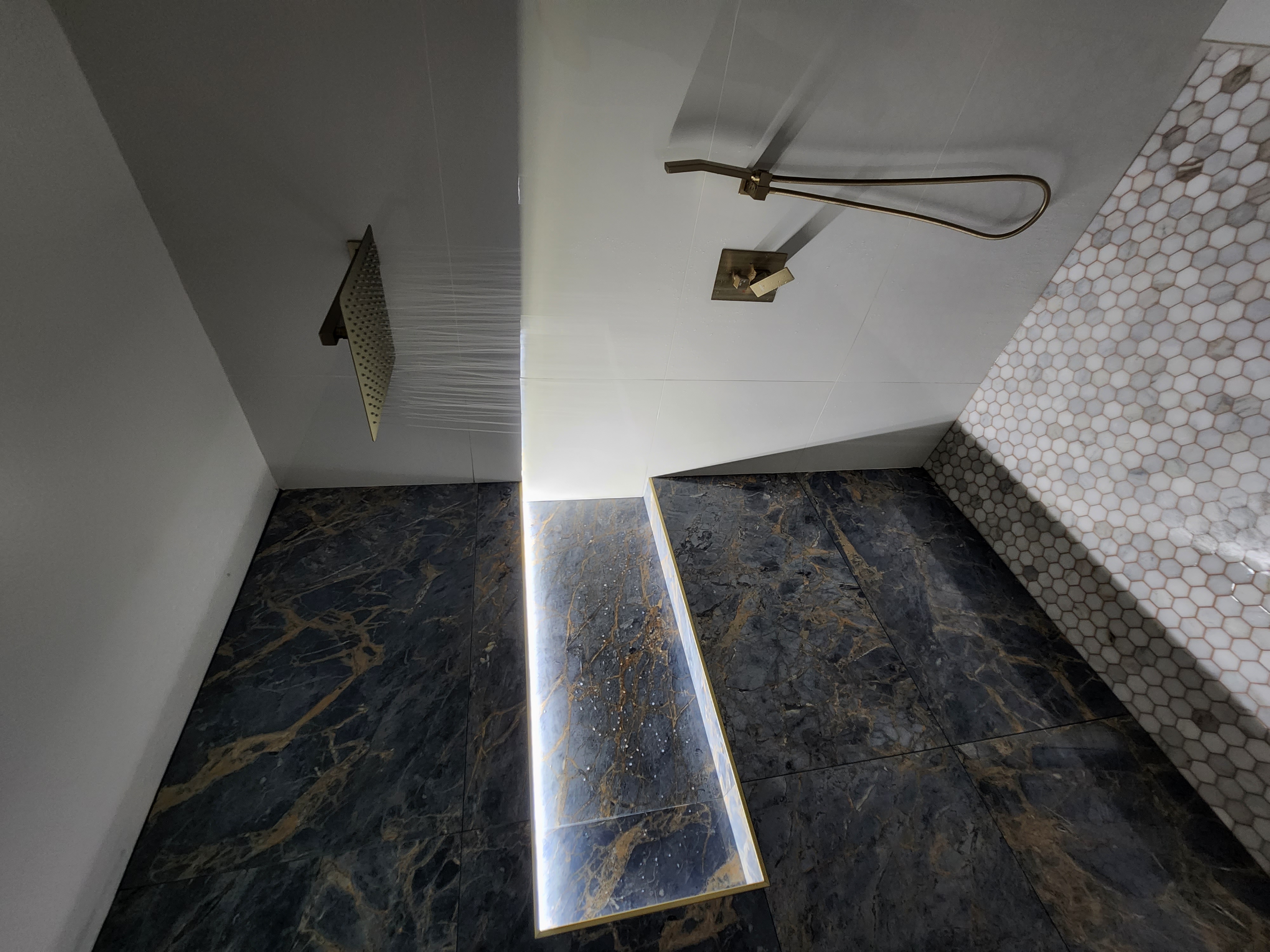 Luxury walk-in shower with gold fixtures and large-format tile